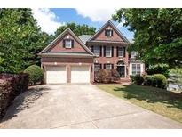 Charming two-story brick home with a two-car garage and well-manicured landscaping at 302 Shawnee Indian Ln, Suwanee, GA 30024