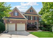 Charming two-story brick home with a two-car garage and a well-manicured front lawn at 302 Shawnee Indian Ln, Suwanee, GA 30024