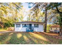 Charming single-story home featuring blue shutters, a covered front porch, and surrounded by mature trees at 3182 Latona Sw Dr, Atlanta, GA 30354