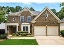 Traditional two-story brick home featuring a two-car garage, symmetrical design and manicured landscaping at 12554 Huntington Trce, Alpharetta, GA 30005