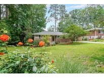 Charming single-story brick home with a lush green lawn and colorful flowers in the landscaped front yard at 2889 Mount Olive Dr, Decatur, GA 30033