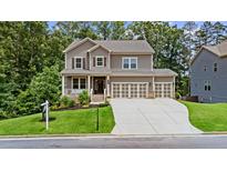 Attractive two-story home featuring a welcoming front porch, three-car garage, and a green lawn at 6045 Stargazer Way, Cumming, GA 30028