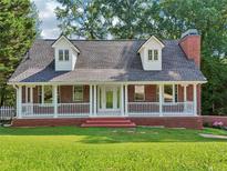 Charming brick home featuring a large covered porch with white columns and dormer windows at 6841 Fairway Ridge Dr, Douglasville, GA 30134