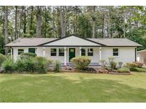 Charming single-story home with white brick, a green door, and a well-manicured lawn and flower bed at 1891 Sahara Se Dr, Atlanta, GA 30316