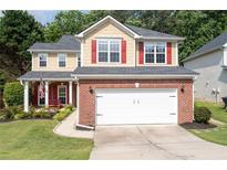 Charming two-story home with brick accents, red shutters, an American flag, a well-manicured lawn and an attached two-car garage at 3362 Palm Nw Cir, Kennesaw, GA 30144