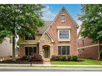 Beautiful two-story brick home featuring manicured landscaping, a stone archway, and a welcoming front porch at 13042 Dartmore Ave, Alpharetta, GA 30005