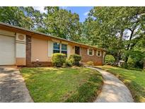 Charming single-story home with a well-manicured lawn, mature trees and curved sidewalk at 1594 Pine Glen Cir, Decatur, GA 30035