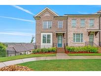 Charming brick townhouse featuring a blue door, manicured lawn, and well-maintained landscaping at 5217 Riden Ct # 263, Buford, GA 30518
