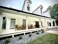 Charming white farmhouse-style home with a welcoming front porch and beautiful landscaping at 128 Golden Hills Dr, Woodstock, GA 30189