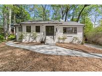 Charming painted brick home with mature trees, landscaping, and inviting front entrance at 3915 Ivy Ne Rd, Atlanta, GA 30342