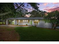 Charming single-story home with white exterior, green door, and a well-manicured lawn at dusk at 4188 Fontana Ct, Tucker, GA 30084