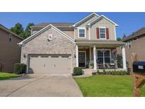 Charming two-story home featuring a brick facade, inviting front porch and well-manicured landscaping at 6298 Pierless Ave, Sugar Hill, GA 30518