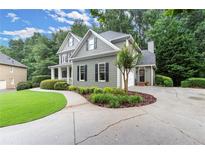 Charming home with gray siding, black shutters, landscaped yard, and a curved driveway at 2015 Samuel Close Ct, Alpharetta, GA 30009