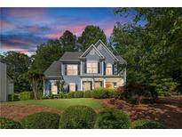Charming two-story home with blue siding, manicured lawn, and mature trees at 1945 Barrett Dr, Cumming, GA 30040