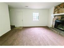 Cozy living room featuring a stone fireplace and neutral carpeting at 1225 Creek Forest Nw Ct, Conyers, GA 30012