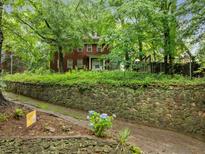 Traditional two-story brick home with a stone retaining wall and mature trees at 1478 Oxford Ne Rd, Atlanta, GA 30307