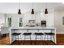 Bright kitchen featuring a marble island with barstool seating and modern pendant lighting at 2493 Oostanaula Ne Dr, Brookhaven, GA 30319