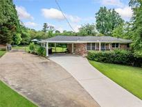 Charming brick home with a long driveway and covered parking area, surrounded by lush greenery at 3190 Crestview Circle Nw Cir, Duluth, GA 30096