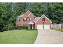 Charming brick home featuring a well-manicured lawn, mature trees, and a two-car garage at 206 Five Iron Nw Ct, Kennesaw, GA 30144