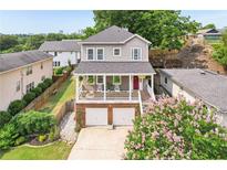 Charming two-story home featuring a covered porch, white railing, red door, and a two-car garage at 218 South Se Ave, Atlanta, GA 30315