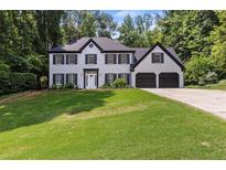Traditional two-story house with brick facade, black shutters, a well manicured lawn and a two car garage at 4220 Singing Post Ne Ln, Roswell, GA 30075