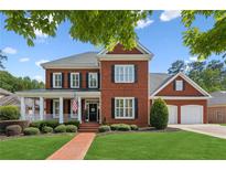 Charming two-story brick home with a welcoming front porch, manicured lawn, and attached two-car garage at 952 Moores Walk Ln, Suwanee, GA 30024