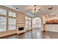 Bright living room featuring hardwood floors, fireplace, and large windows with a view to the kitchen at 2280 Copper Trail Ln, Buford, GA 30519