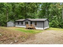 Charming gray home with a wooden deck, mature trees and a small storage shed at 1010 Martin Ln, Canton, GA 30114