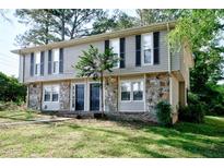 Traditional two-story home with stone accents, black shutters, and a well-maintained lawn at 1142 Forest Villa Nw Dr, Conyers, GA 30012