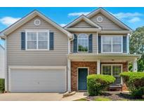 Charming two-story home with a well-maintained lawn, attached garage, and inviting blue door at 207 Diamond Valley Pass, Canton, GA 30114