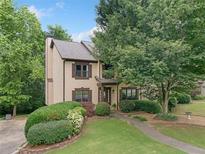 Stucco and wood facade is surrounded by mature trees and has manicured landscaping at 404 Pine Grove Way, Woodstock, GA 30189