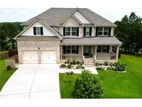 Charming two-story brick home boasts a manicured lawn, two-car garage, and inviting front porch at 909 Shatley Dr, Stockbridge, GA 30281