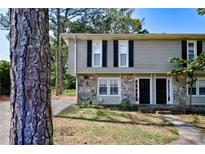Two-story townhome featuring gray siding, stone accents, and black shutters at 1140 Forest Villa Nw Dr, Conyers, GA 30012