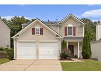 Two-story home with a two car garage, neutral siding, and landscaped front yard at 325 Meadows Ln, Canton, GA 30114