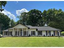 Charming single story home with white brick, black shutters and beautifully manicured lawn at 5631 Queensborough Dr, Atlanta, GA 30338