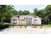 Charming stucco home with gray trim, arched windows, and mature landscaping at 1916 Highway 138 Sw, Conyers, GA 30094