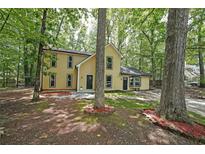 Charming yellow two-story home surrounded by mature trees and landscaping at 7156 Whitfield Drive Dr, Riverdale, GA 30296