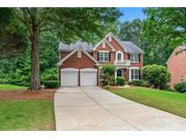 Charming brick home with well-manicured lawn, mature trees, and a two-car garage at 1115 Ballington Dr, Cumming, GA 30041