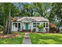 Charming home featuring a manicured lawn, light-colored facade, and inviting front porch with a bright teal front door at 2485 Hillside Ave, Decatur, GA 30032