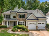 Charming home featuring stone accents, a well-manicured lawn, an attached two-car garage, and a welcoming front porch at 1205 Compass Pointe Xing, Alpharetta, GA 30005