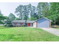 Ranch home with gray brick, siding, shutters and trim, and red front door on well manicured lawn at 2173 Martin Way, Jonesboro, GA 30236