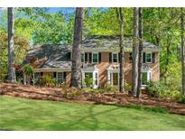 Beautiful brick home with manicured lawn, mature trees, and bay windows at 3402 Johnson Ferry Rd, Roswell, GA 30075