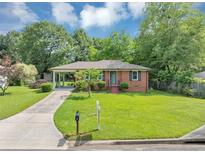Charming brick home with a well-maintained lawn, a covered carport, and a neatly paved driveway at 701 Green Acres Se Rd, Smyrna, GA 30080