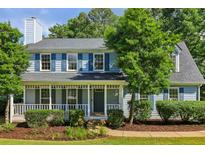 Charming two-story home with a covered front porch, blue shutters, and manicured landscaping at 3970 Genoa Ct, Duluth, GA 30096