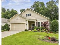 Charming beige home featuring a well-manicured lawn, complemented by a lovely garden and two-car garage at 5105 Kings Common Way, Cumming, GA 30040