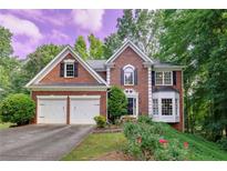 Charming two-story brick home with a two-car garage and manicured front lawn with beautiful roses at 6302 Manassas Nw Pass, Acworth, GA 30101
