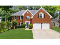 Attractive two-story brick home with an attached two-car garage, manicured lawn, and shade trees at 10865 Misty Moon Ct, Alpharetta, GA 30022