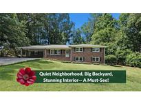 Charming brick home featuring a lush green lawn and mature trees at 1850 Donald Dr, Marietta, GA 30062