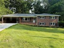 Charming brick home featuring a well-manicured lawn, covered porch, and mature trees at 1850 Donald Dr, Marietta, GA 30062