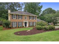 Charming two-story brick home with a manicured lawn and lush landscaping at 1338 Nonie Way, Marietta, GA 30062